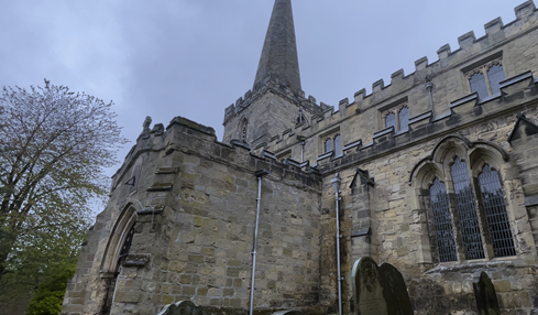 A stone building with a pointed tower
Description automatically generated